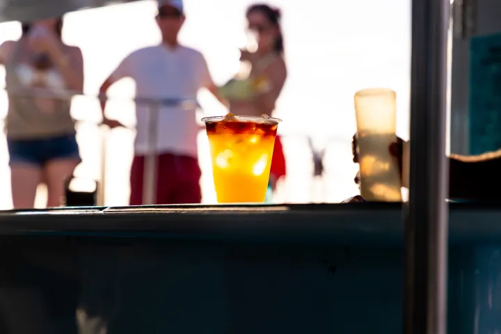 Colorful drink on counter with blurred people in background during sunset.